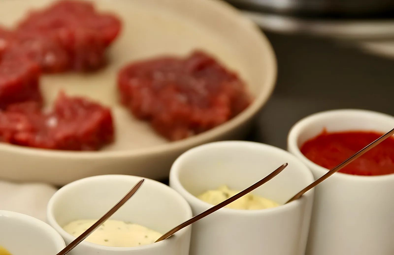 Carne cruda junto a los cuencos de las salsas de la casa